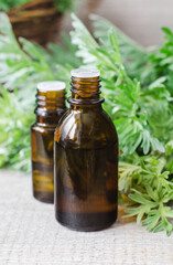 Small bottle with essential wormwood oil (extract, tincture, infusion). Old wooden background. Aromatherapy, spa and herbal medicine concept.