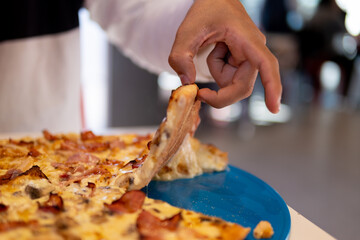 Faceless patron grips delectable pizza slice.