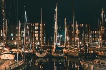 Foto auf Leinwand The Hague, Netherlands - January 1, 2020: Scenic panorama of Scheveningen harbour. Romantic modern seaside resort. Brown brick buildings, light windows, moored white yachts and sailboats in evening. © goncharovaia