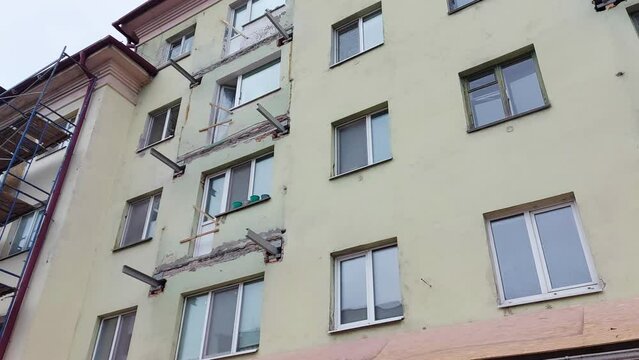 Scaffolding along an old multi-storey building in the city. Reconstruction and repair of window frames, facades, production of new balconies, industry