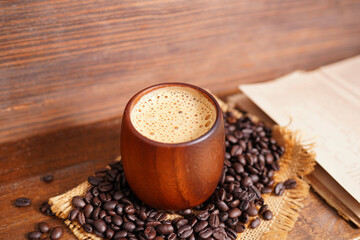 Hot coffee, cappuccino in a wooden cup and roasted coffee beans.