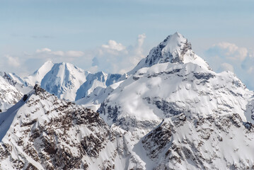 Snow-covered winter mountains of the Caucasus on a sunny day. Panoramic view from the ski slope of Elbrus, Kabardino-Balkaria, Russia - 696354513