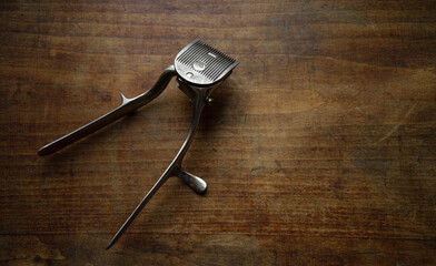 A hand-held hair clipper on a vintage wooden table.Barbershop in retro style.The design of a...