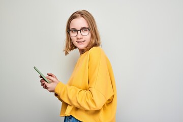 Portrait of young blond woman holding mobile phone in hand with happy smiling face. Person with smartphone isolated on white background.