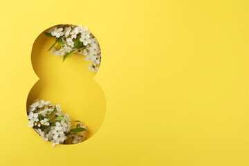 8 March greeting card. Paper cut Eight made of yellow background and fresh spring flowers bouquet of blossoming cherry and apple trees. Greeting card for Womens Day on March 8 Flat lay, top view.