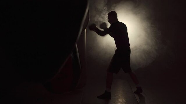 Boxer training in the gym hitting a punching bag with gloves. moment of impact on punching bag.