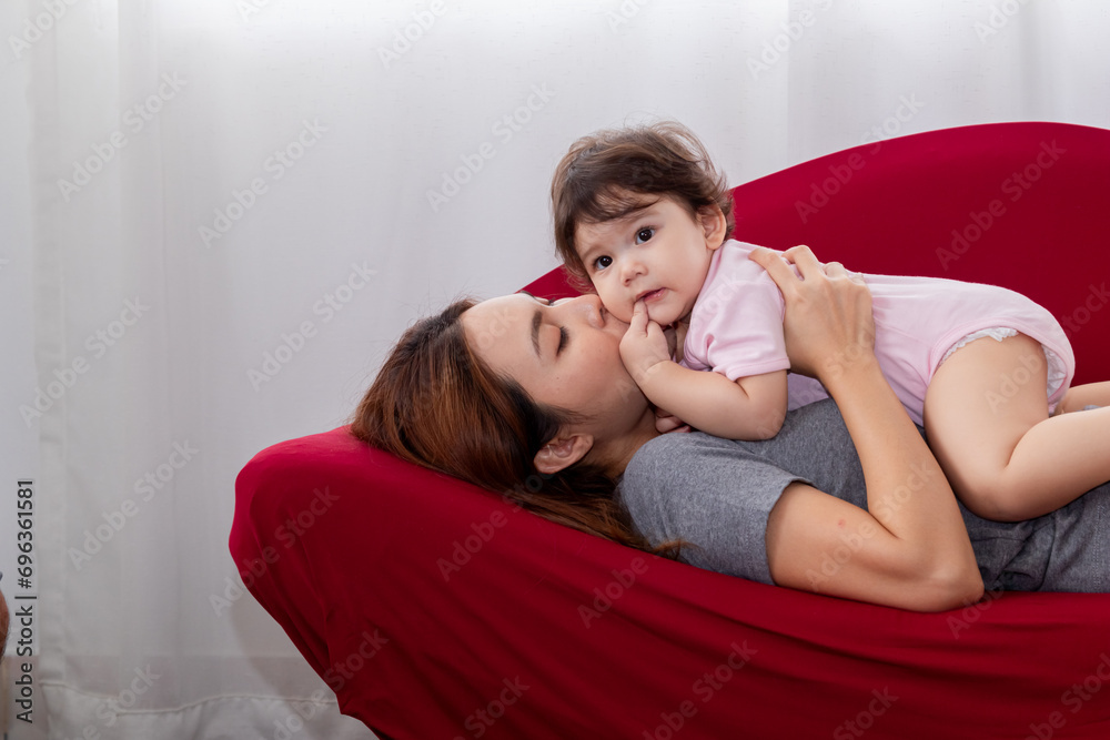 Wall mural close-up asian female nurturing toddler girl infant at home having fun with love care bonding tender