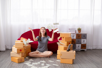 Happy freelance Asian female selling online sitting with many cardboard boxes in living room with...