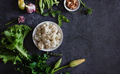 Cauliflower with vegetables and spices on a dark wood background