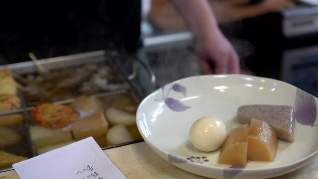 Chef preparing egg and kojac jaoden hot boild daikon radish in Japanese style soup hot meal