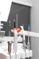 Close-up of dental instruments in the dentist's office, selective focus. Polymerization lamp, a saliva pump, a device for supplying water and air. Vertical photo