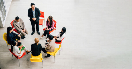 From above, diverse group collaborates in bustling office, engaged in teamwork and discussions. A businessman and businesswoman sit at a conference, providing space for your business meeting concept. - obrazy, fototapety, plakaty