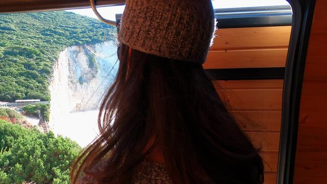 Woman opening camper van door looking at iconic Porto Katsiki beach in Lefkada island, in Greece
