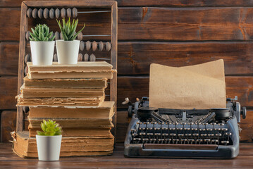 Retro style typewriter, stack of books and abacus on the table. Front view. Education concept...