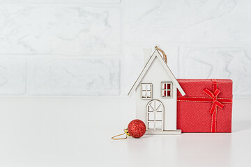 White House - toy, red gift box on a light background. Copy space. Give or buy a cottage for Christmas
