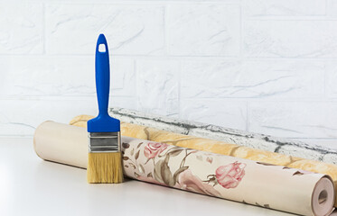 A brush and rolls of wallpaper with multi-colored patterns are prepared for renovating a house or apartment. Room renovation concept