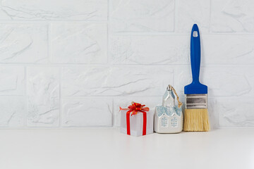 Brush for repair, house - toy and gift on a light background. Copy space. Renovation as a Christmas gift