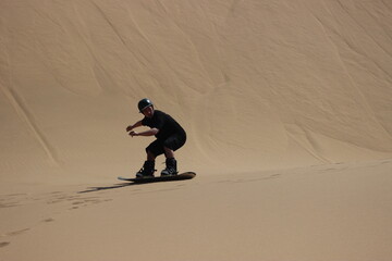 Sandboarding over a dune in the Namibian Desert