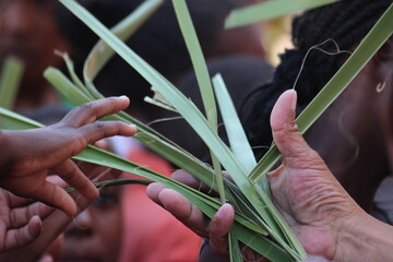 Priests hand handing out palm leaves during religious ceremony to childs hand