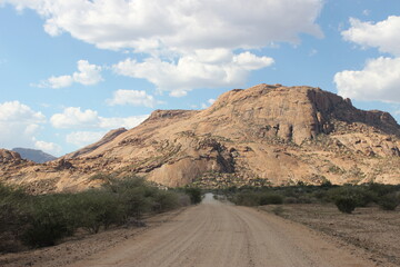 Street view from a car on a sand road with a desert mountain in Namibia

