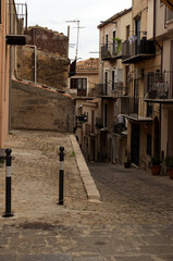 Authentic narrow cobblestone street between vintage residential houses. Traditional street in medieval village Castelbuono. Underwear drying on the balcony fence. Travel and tourism concept