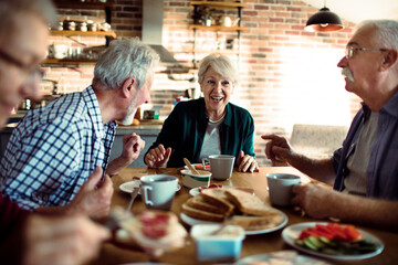 Happy senior people eating together at home