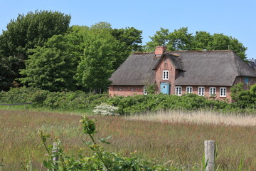 Fototapeta na wymiar Historiches Haus hinter einem Deich in der Nähe der Stadt Westerland auf der Nordseeinsel Sylt