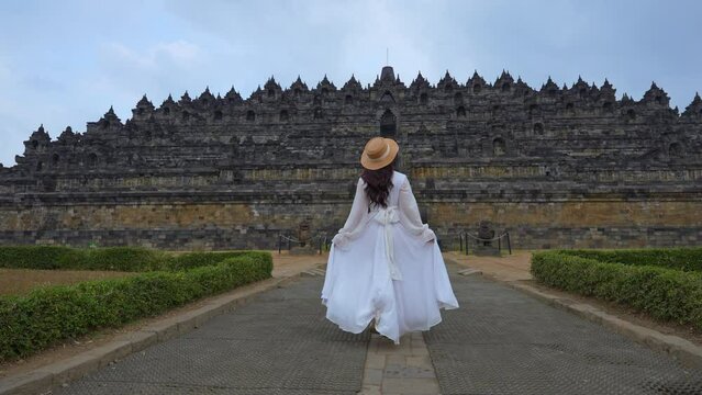 4k slow motion video. Female tourist in white dress with Borobudur Temple in Magelang, Yogyakarta, on the island of Java, Indonesia.