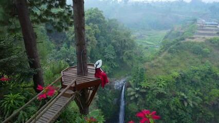 Female tourist at the viewpoint of Air Terjun Kedung Kayang Waterfall, Indonesia.