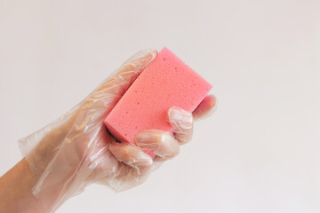 Cleaning the room, sponge in hand close-up. Female hand in a glove with a sponge for washing dishes...