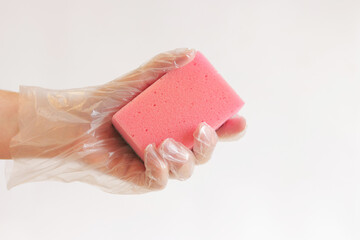 Cleaning the room, sponge in hand close-up. Female hand in a glove with a sponge for washing dishes...