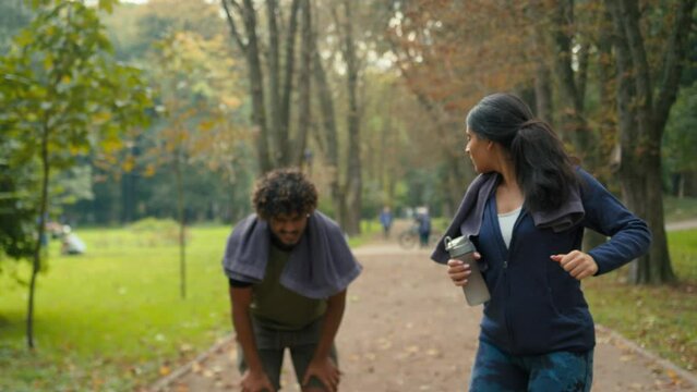 Two people Arabian couple Indian male female running together sport run jogging in park outdoors active morning slimming fitness tired unwell exhausted man stop rest feel pain woman support calming