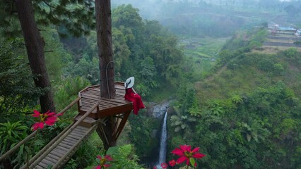 Female tourist at the viewpoint of Air Terjun Kedung Kayang Waterfall, Indonesia.