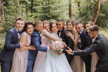 full-length portrait of the newlyweds and their friends at the wedding. The bride and groom with bridesmaids and friends of the groom are having fun and rejoicing at the wedding.
