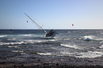 Sailing boat of tourists keel over at rocky shore (El Medano, Tenerife Island, Spain)