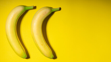 2 Yellow bananas arranged on a yellow background.