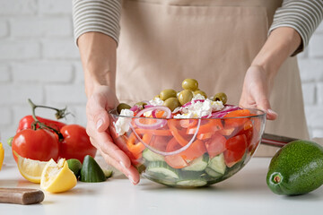 Woman holding bowl of Greek salad