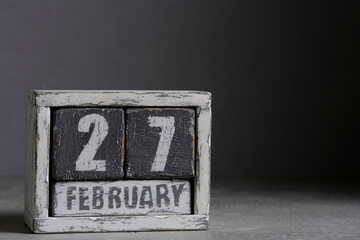 February 27 on wooden calendar, on dark gray background.