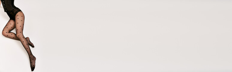 cropped banner of glamorous woman in black corset and polka dot tights lying on white backdrop