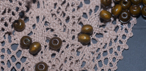 wooden  beads on the lace openwork, hobby and creativity. - obrazy, fototapety, plakaty