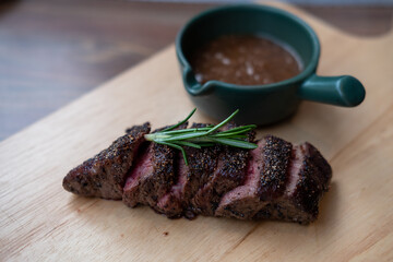 Medium rare sliced meat on wooden plate with sauce