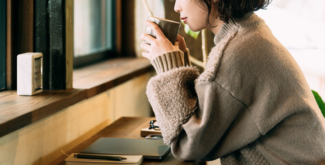 カウンターで温かい飲み物を飲む笑顔の女性