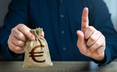 A man warns with his finger offering a euro money bag. Bad credit history. Funding and grants....