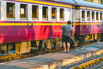 Male janitor clean and wash exterior of train. Worker cleaning the train on railways at train...