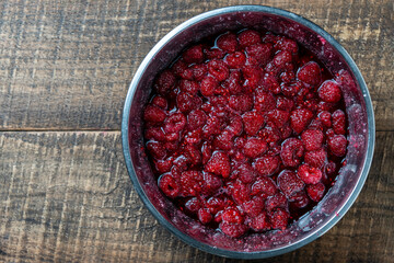 Fresh red raspberry berry, covered with granulated sugar for jam preparation in bowl, top view, closeup. Background and texture of raspberries with sugar