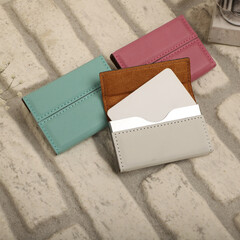 Colored leather business card holder, Genuine leather business card holder, concept shot, top view, different color, clamshell and stitched card holder. white wall background.