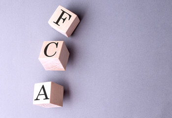 Word FCA on wooden block on the grey background