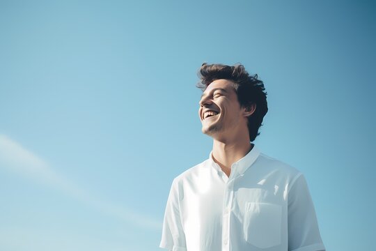 A Cheerful Man In A Crisp White Shirt Against A Soft Sky-blue Backdrop, Beaming With Joy.