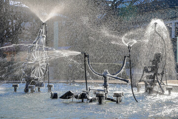 The Tinguely fountain in the city center Basel with partly frozen parts and splashing in backlit in cold winter weather