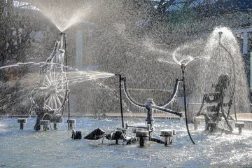 The Tinguely fountain in the city center Basel with partly frozen parts and splashing in backlit in cold winter weather © Yü Lan
